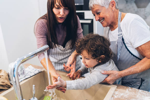 Washing hands Mother and grandmother washing her little boy's hands in the kitchen hand-hygiene-day stock pictures, royalty-free photos & images