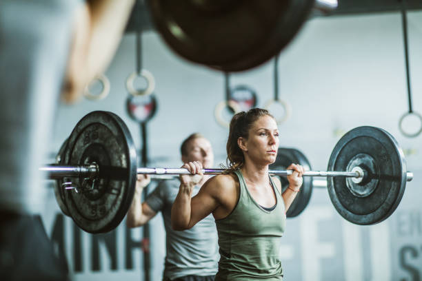istock Muscular build woman lifting barbell during training class in a gym. 1143901242