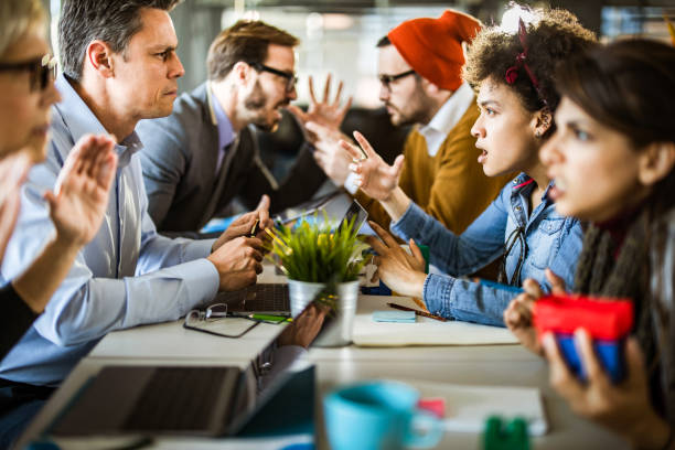 Confrontation among business people and creative people! Business people arguing with young creative people on a meeting in the office. Focus is on people in the middle. communication problems stock pictures, royalty-free photos & images