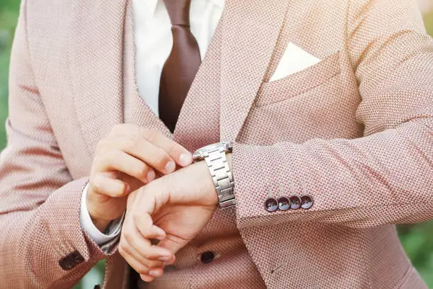 Photo of Styled man in vintage suit looking at his luxury wristwatch
