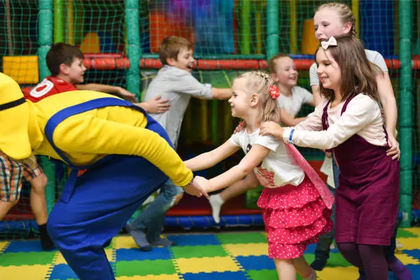 A group of children at a party play, run for the animator and hold hands.