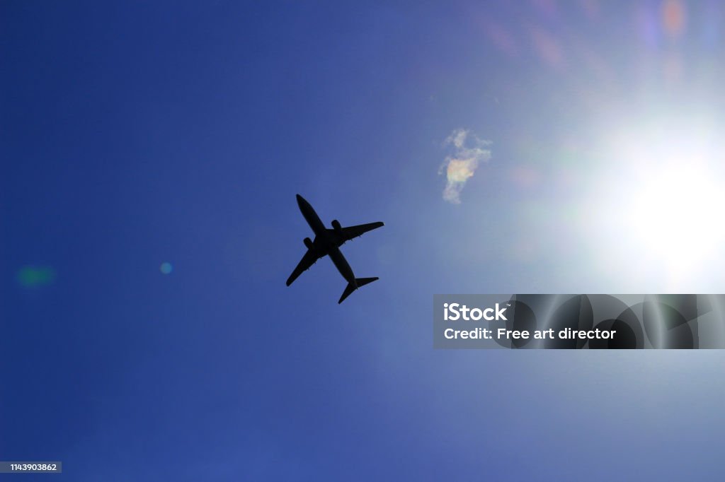 Silhouette of a jetliner flying in a blue sky where the sun shines Travel scene Air Vehicle Stock Photo