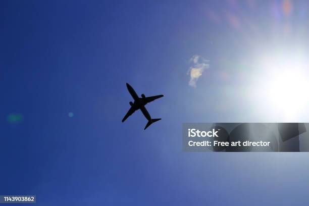 Silhouette Of A Jetliner Flying In A Blue Sky Where The Sun Shines Stock Photo - Download Image Now