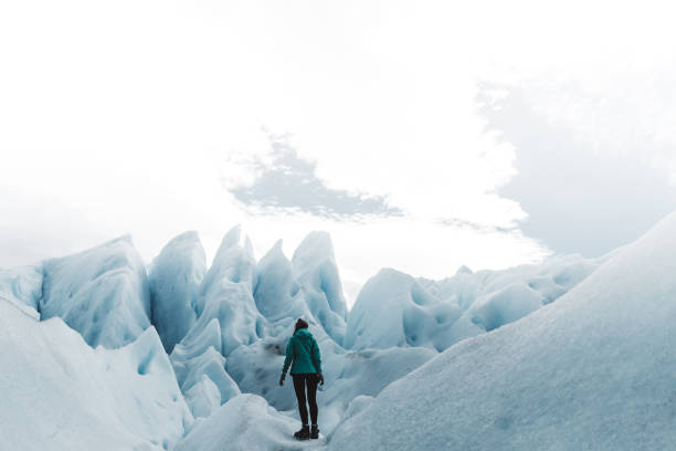 Silhouette of woman in green jacket enjoying her hiking trip on beautiful turquoise colored glacier Perito Moreno in Argentinian Patagonia