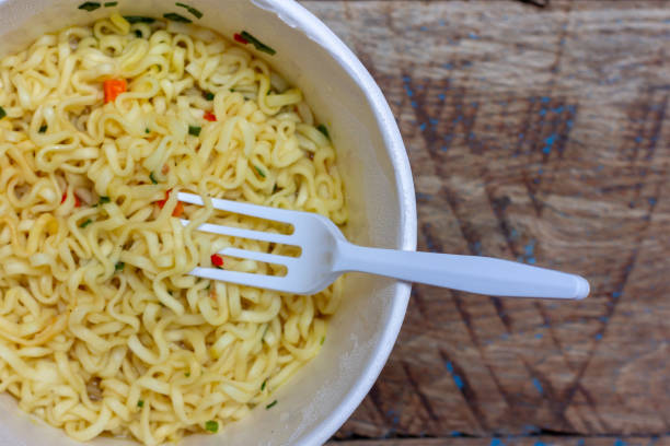 istock instant noodles and plastic fork on wooden background, top view closeup 1143912251