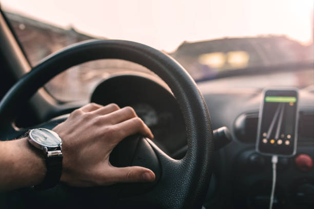 istock driver with a wristwatch rides through the city using a navigator on a smartphone on a sunny day. 1143914174