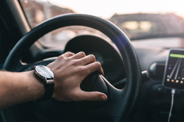 istock driver with a wristwatch rides through the city using a navigator on a smartphone on a sunny day. 1143915544