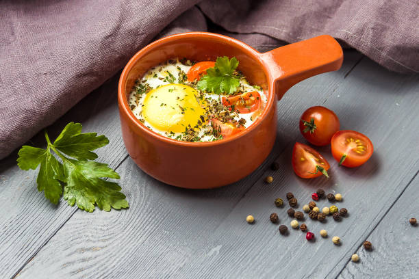 Portioned baked eggs in ceramic cocotte on gray wooden table, breakfast. copy space for you text. stock photo