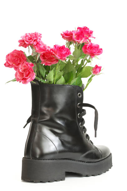 istock Bunch of pink roses in black combat boot 1143917935