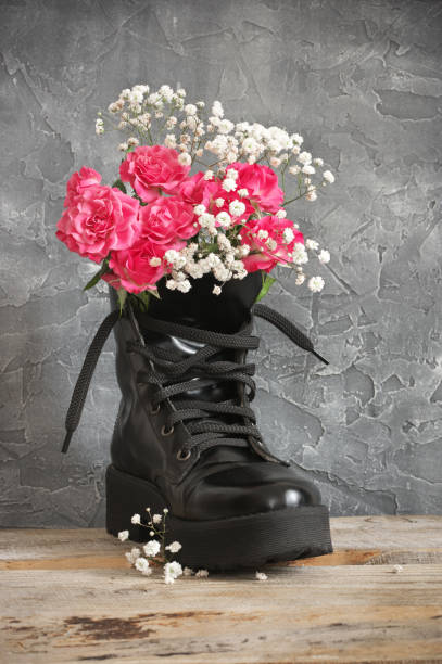 istock Bunch of flowers in black combat boot 1143917940
