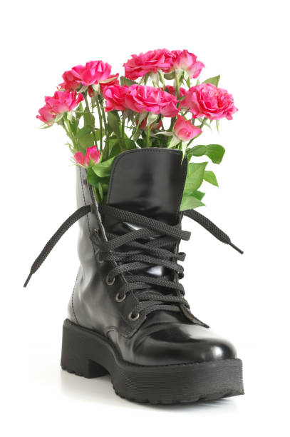 istock Bunch of pink roses in black combat boot 1143917947