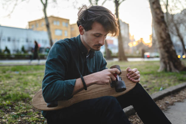 istock Handsome and well-dressed hipster skateboarder fixing his skateboard 1143921767
