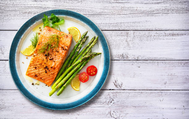 bistecca di salmone alla griglia guarnita con asparagi verdi, limone e pomodori - green steak food gourmet foto e immagini stock