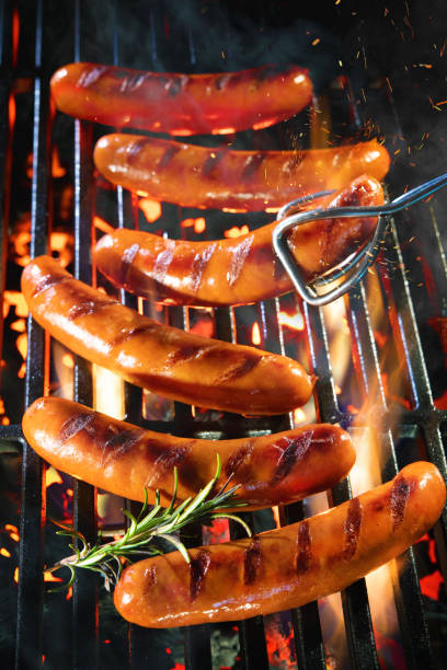 deliciosas salchichas chispeando sobre las brasas en la parrilla de barbacoa - sausage bratwurst barbecue grill barbecue fotografías e imágenes de stock