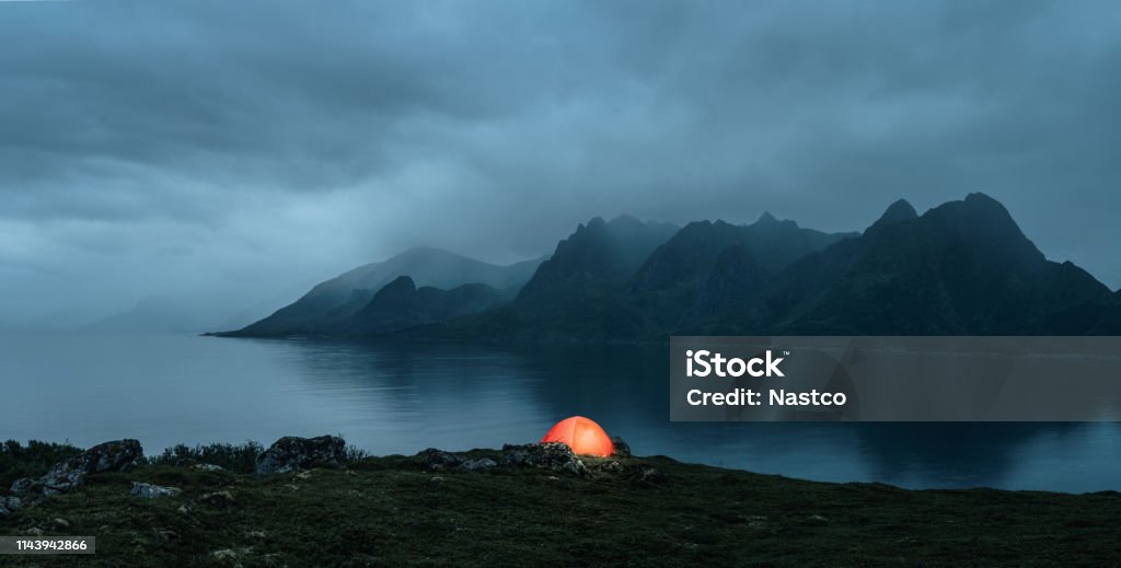 Illuminated tent at the lofoten islands Illuminated tent at the lofoten islands on the rainy evening with copy space Night Stock Photo