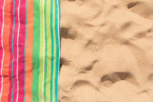 Beach towel on sandy tropical beach top view with copy space