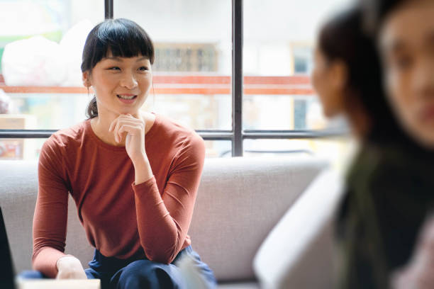 Female Young Asian Entrepreneur smiling and discussing ideas with colleague stock photo