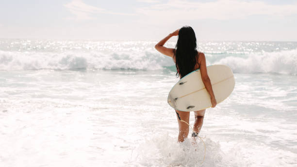istock Female surfer going on surf in the sea 1143950811