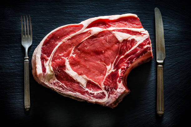 Raw rib steak shot from above on black background