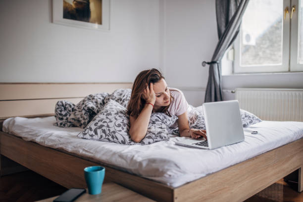 istock Young woman using laptop in the bed 1143952104