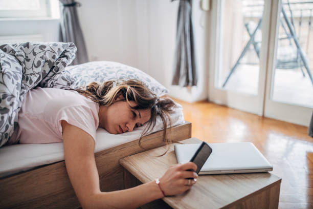 Sleepy young woman Young woman is waking up and looking at her smart phone. turning on or off photos stock pictures, royalty-free photos & images