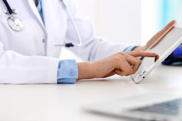 istock Doctor working table. Woman physician using tablet computer while sitting in hospital office close-up. Healthcare, insurance and medicine concept. 1143958889
