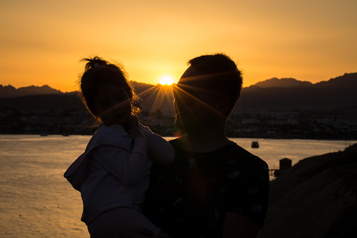 Silhouette of father with his daughter at sunset in Egypt. Sharm El Sheikh.
