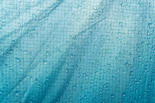 Green fabric with water drops as background. Water drops on tent awning. Protection, shelter from rain. stock photo