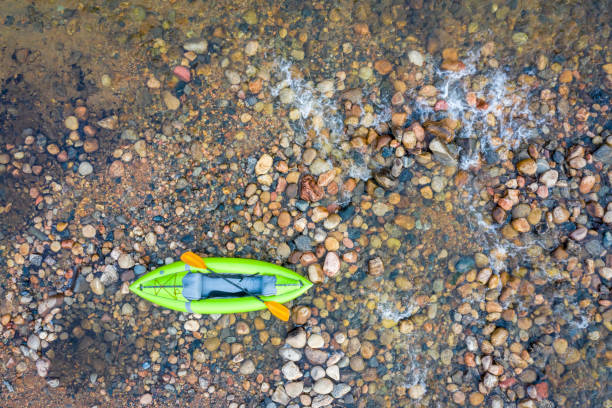 Summer vacations by the river. Man relaxing on an inflatable tub being towed by a kayak. Peaceful scenery of water and surrounding lush forests