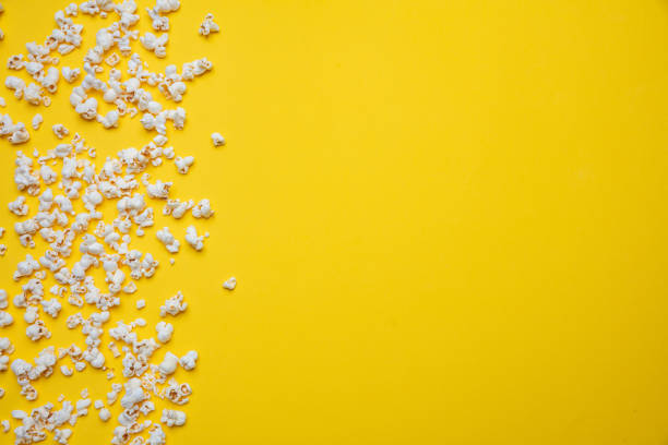 istock Pop corn scattered on yellow color background, top view 1143972492