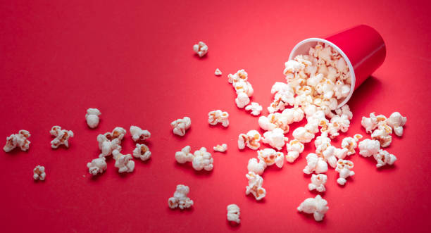 istock Pop corn scattered on red color background, closeup view 1143972540