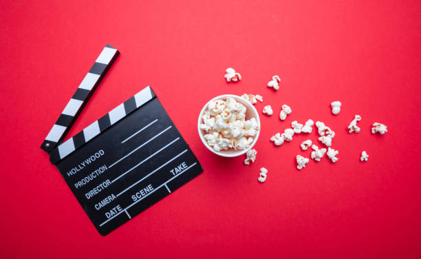istock Clapperboard and pop corn on red color background, top view 1143972550