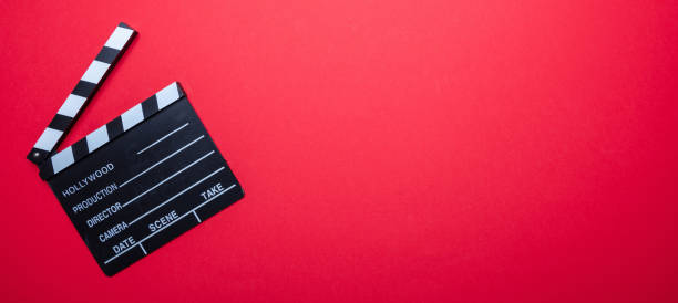 istock Movie clapperboard on red color background, banner, top view 1143972552