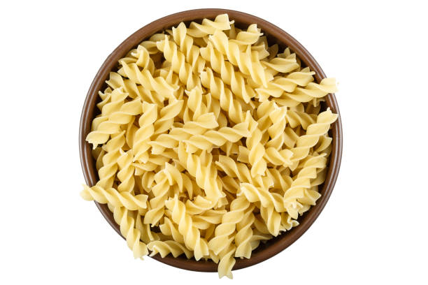 istock uncooked spiral pasta in a plate. isolated on a white background. 1143972901