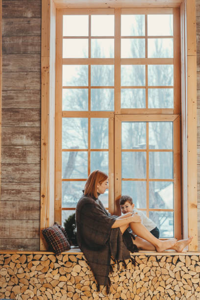 istock Mom and son sitting on the windowsill and playing. 1143976522