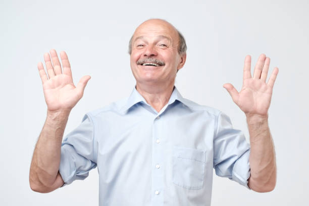 istock Cheerful guy raises hands as shows being uninvolved, has happy look 1143978510