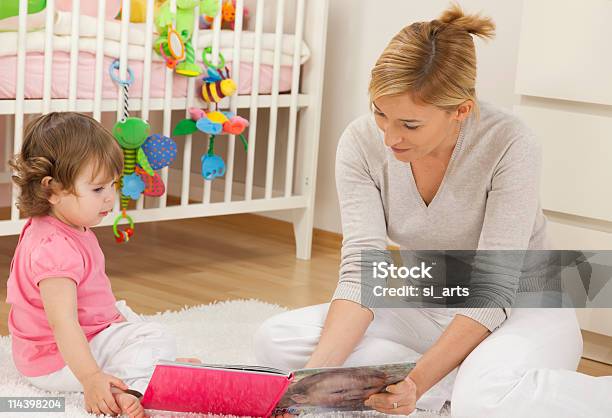 Madre Mirando Libro Con Su Bebé Niña Foto de stock y más banco de imágenes de 30-34 años - 30-34 años, Adulto, Adulto de mediana edad