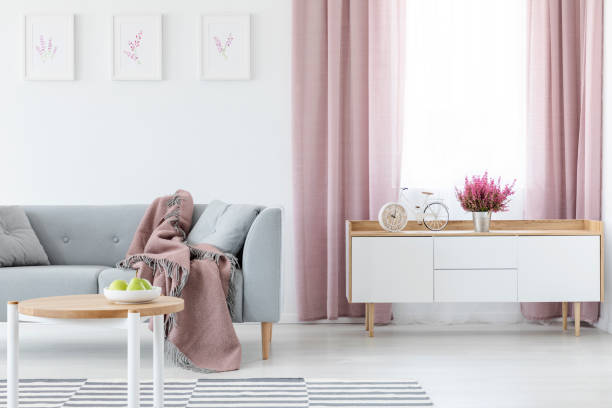 couverture sur canapé gris dans un salon élégant intérieur avec armoire en bois blanc et table basse, tapis rayé et rideaux lilas, vraie photo - coffee table living room indoors comfortable photos et images de collection