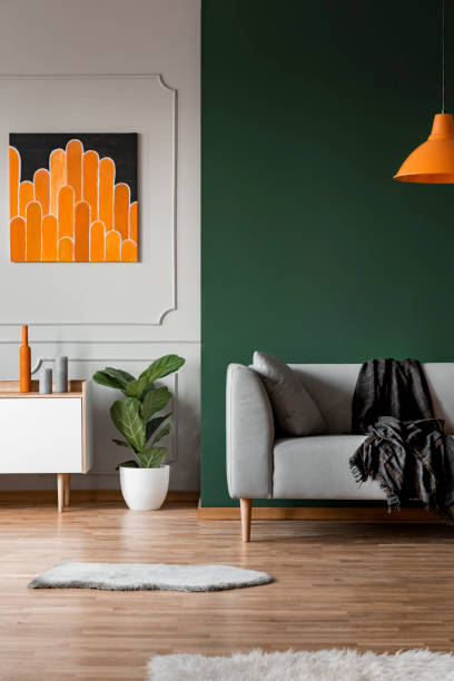 istock Dark green wall in grey and orange living room interior 1143990726