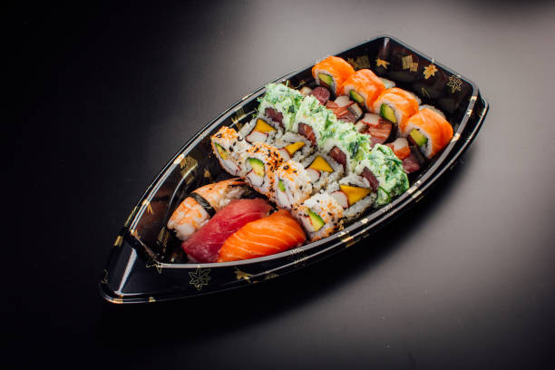 Japanese cuisine. Sushi set on a plastic ship over dark background.