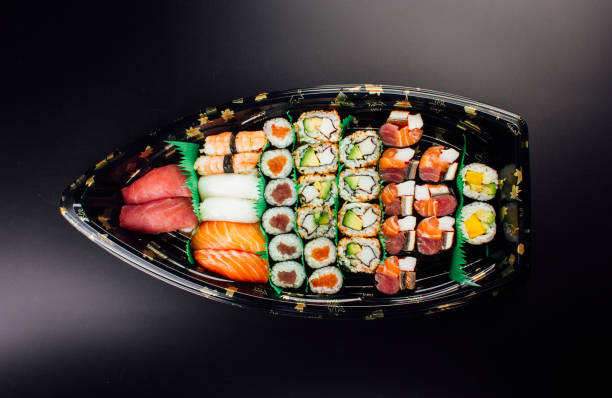 Japanese cuisine. Sushi set on a plastic ship over dark background.
