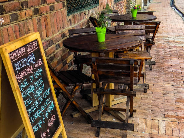 Wooden tables and chairs next to restaurant menu in Spanish