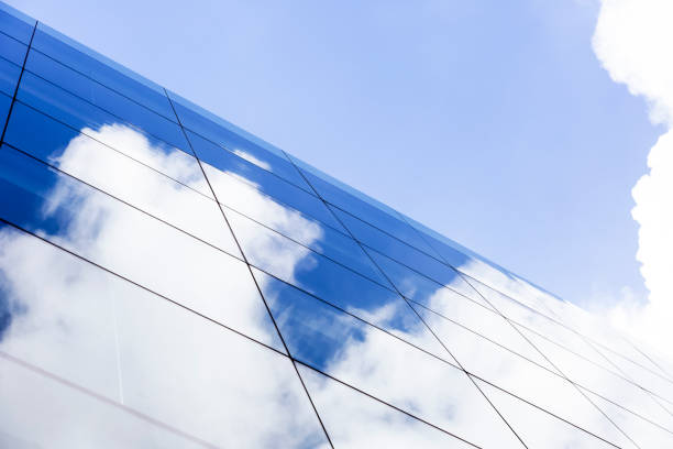 reflexo do céu azul e das nuvens na parede de vidro do arranha-céus, fundo com espaço da cópia - reflection glass surrounding wall urban scene - fotografias e filmes do acervo