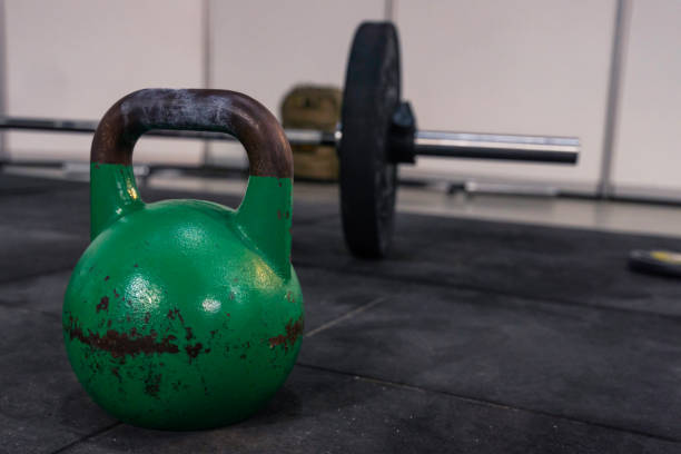 istock Kettlebell on a rubber mat, barbell ready for exercise in the background. Sporting equipment used in a cross training and gym physical exercise systems. 1143996290