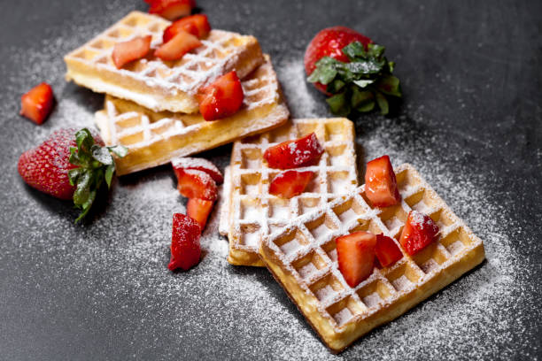 Belgium waffers with strawberries and sugar powder on black board background. stock photo