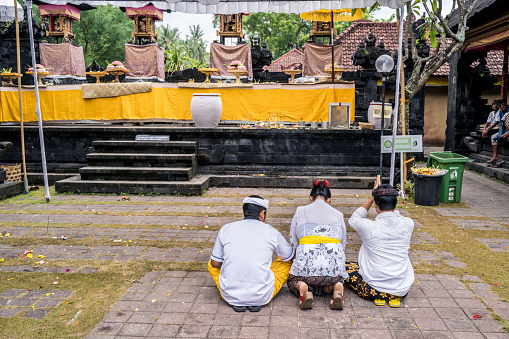 Balinese family dressed in a traditional costumes praying in Pura Goa Lawah (Balinese 
