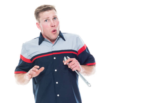 Young attractive male mechanic standing on white background - shock