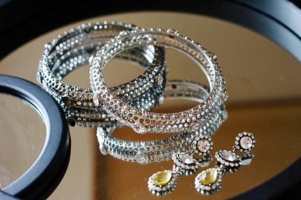 istock A silver bangle and  a pair of silver earrings on a mirror trimmed in black 1144009305