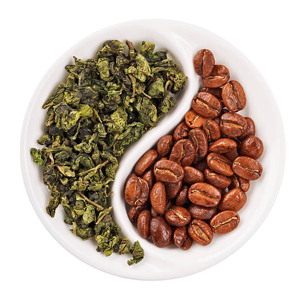 Green leaf tea versus coffee beans in Yin Yang plate stock photo