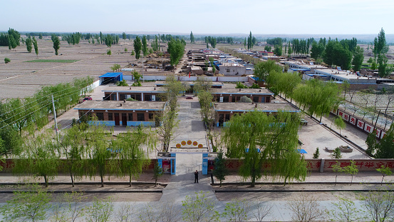 Aerial view of small little poor village with school in the middle of dry farm land desert, Gansu, China